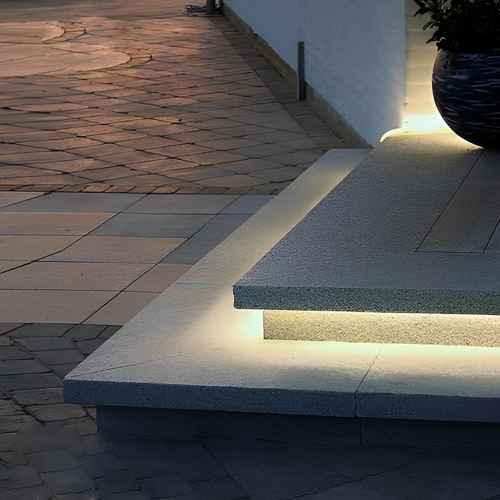 Outdoor embedded LED light strips illuminating a cozy outdoor seating area.