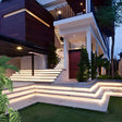 Outdoor embedded LED light strips casting a gentle glow along curved staircase edges.